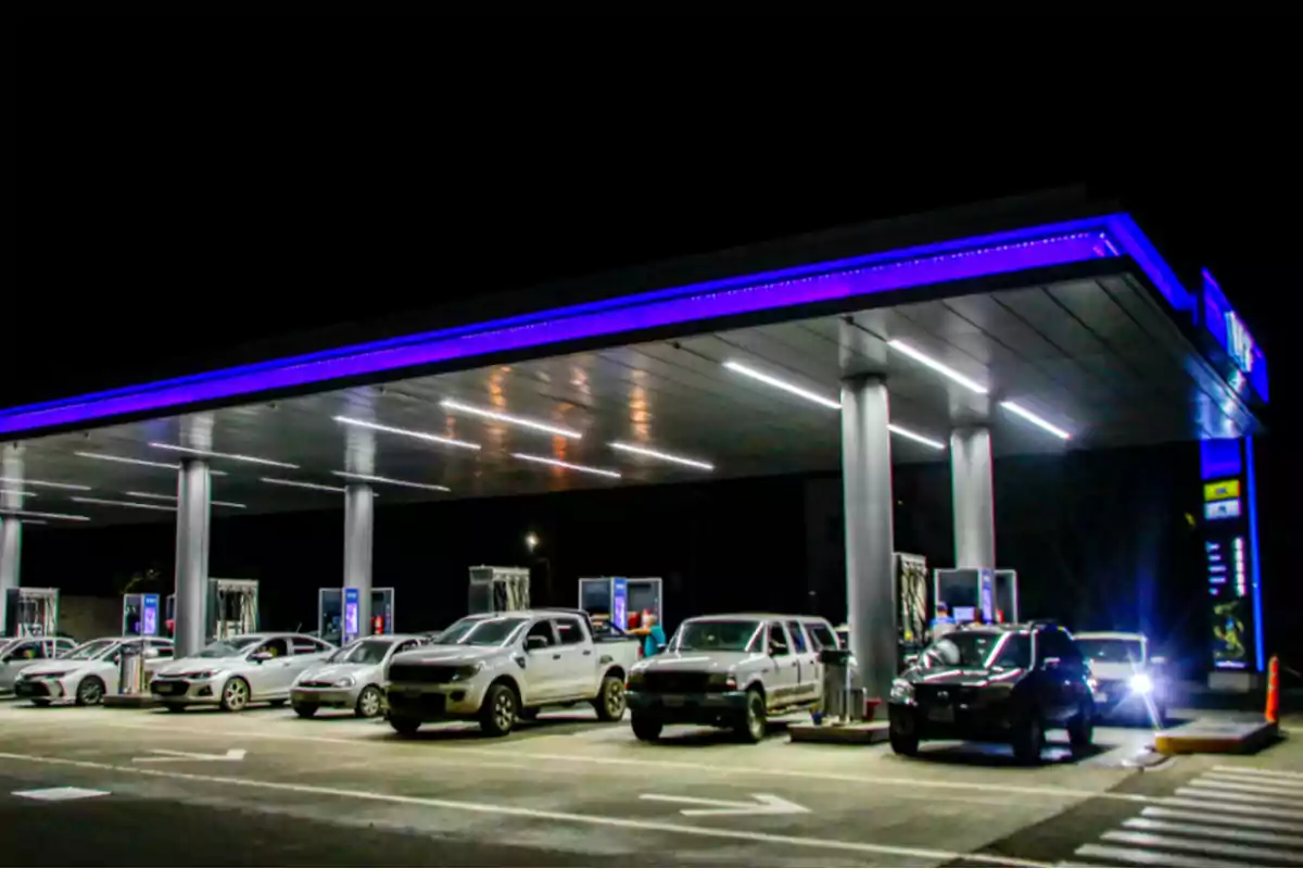 Varios autos estacionados en una estación de servicio iluminada durante la noche