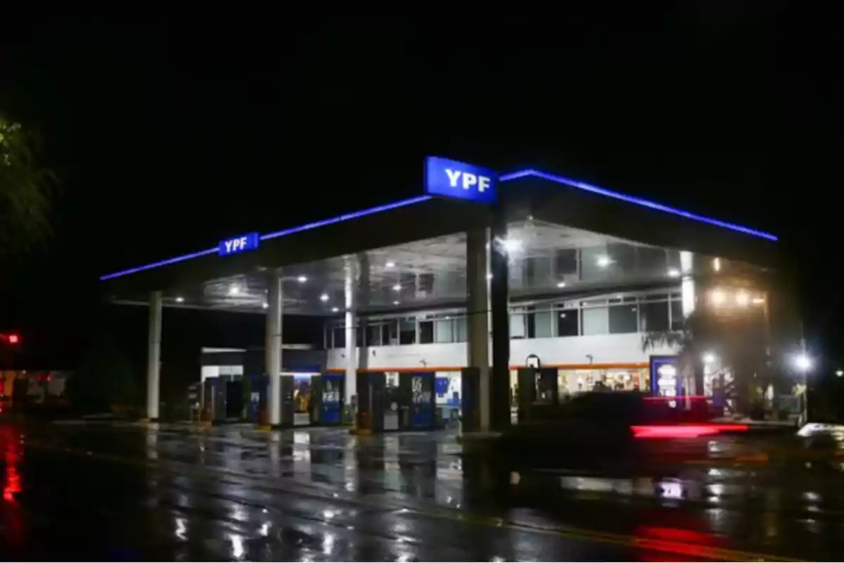 Estación de servicio YPF iluminada durante la noche con reflejos en el pavimento mojado Estación de servicio YPF iluminada durante la noche con reflejos en el pavimento mojado