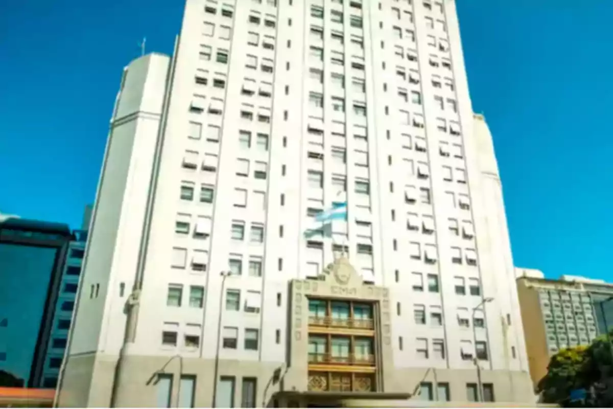 Tall Art Deco government building with an Argentine flag waving in the center and a clear sky in the background Tall Art Deco government building with an Argentine flag waving in the center and a clear sky in the background