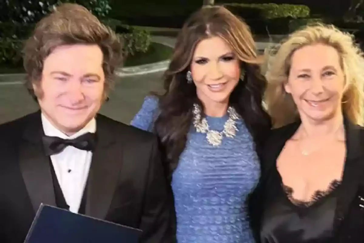 Tres personas posan sonrientes para una foto en un evento elegante al aire libre, una de ellas lleva esmoquin y las otras dos visten ropa formal Tres personas posan sonrientes para una foto en un evento elegante al aire libre, una de ellas lleva esmoquin y las otras dos visten ropa formal