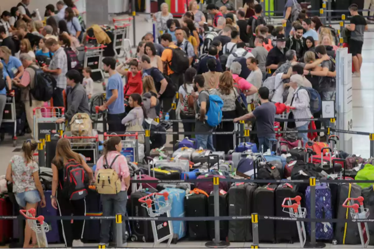 Personas haciendo fila en un aeropuerto con muchos equipajes y carritos alrededor Personas haciendo fila en un aeropuerto con muchos equipajes y carritos alrededor