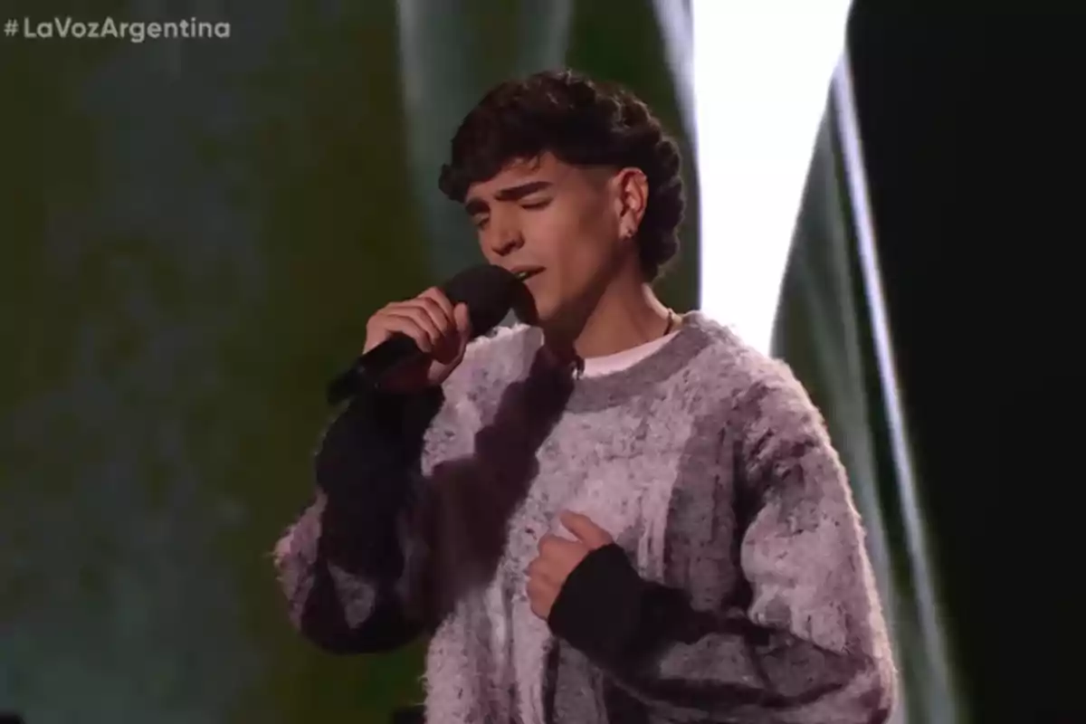 Joven cantando en un escenario con un micrófono en la mano y expresión concentrada Joven cantando en un escenario con un micrófono en la mano y expresión concentrada