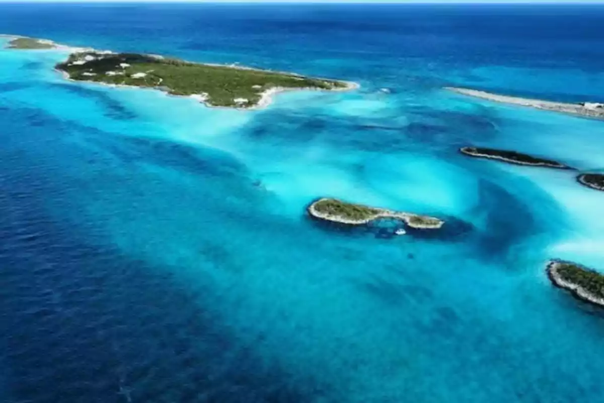 Vista aérea de una isla rodeada de aguas turquesa y azul profundo en el mar. Vista aérea de una isla rodeada de aguas turquesa y azul profundo en el mar.