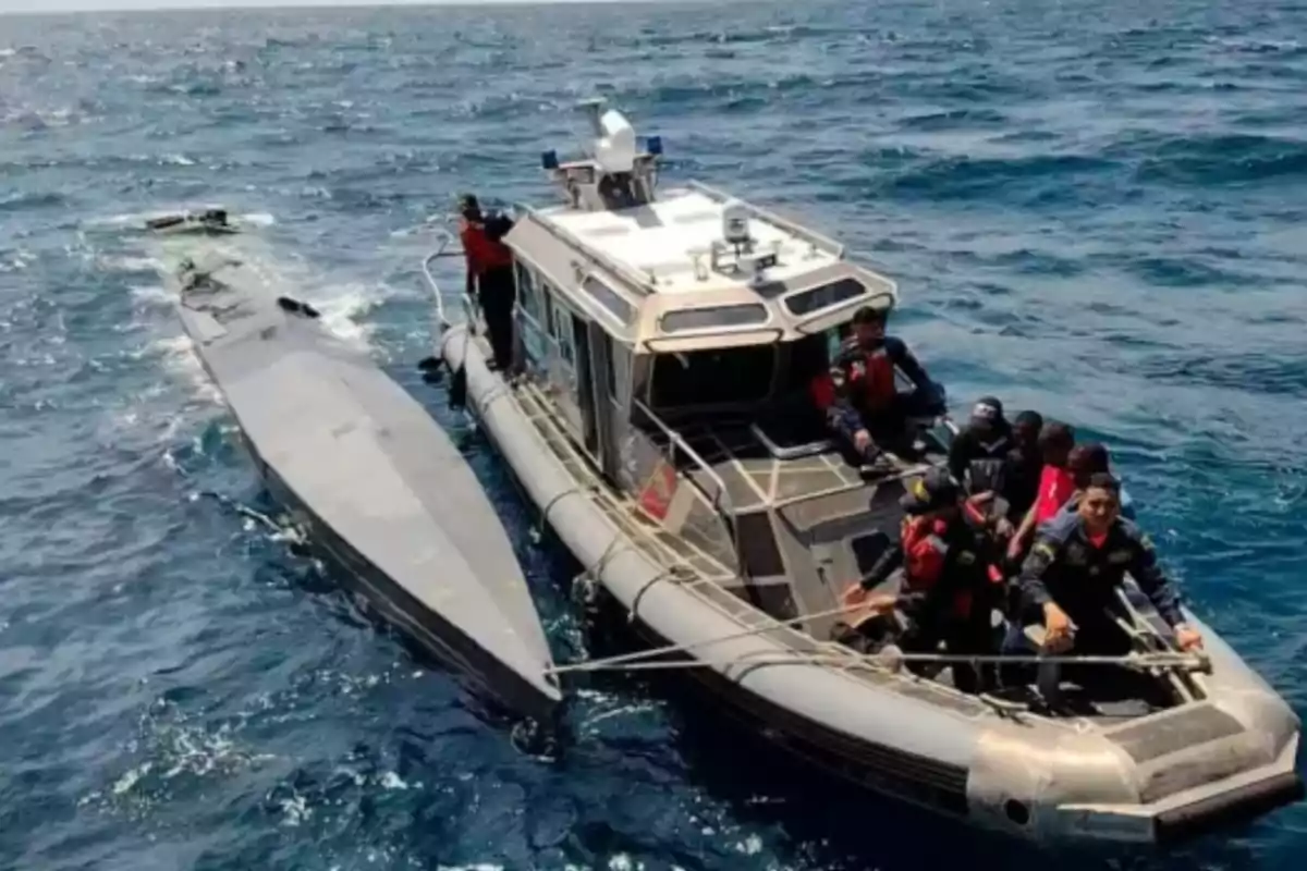 Una lancha de la marina con varios tripulantes escolta un semisumergible gris en medio del océano Una lancha de la marina con varios tripulantes escolta un semisumergible gris en medio del océano