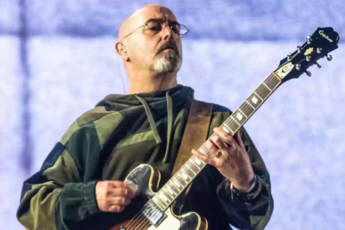 Hombre calvo con barba y gafas tocando una guitarra eléctrica en el escenario Hombre calvo con barba y gafas tocando una guitarra eléctrica en el escenario