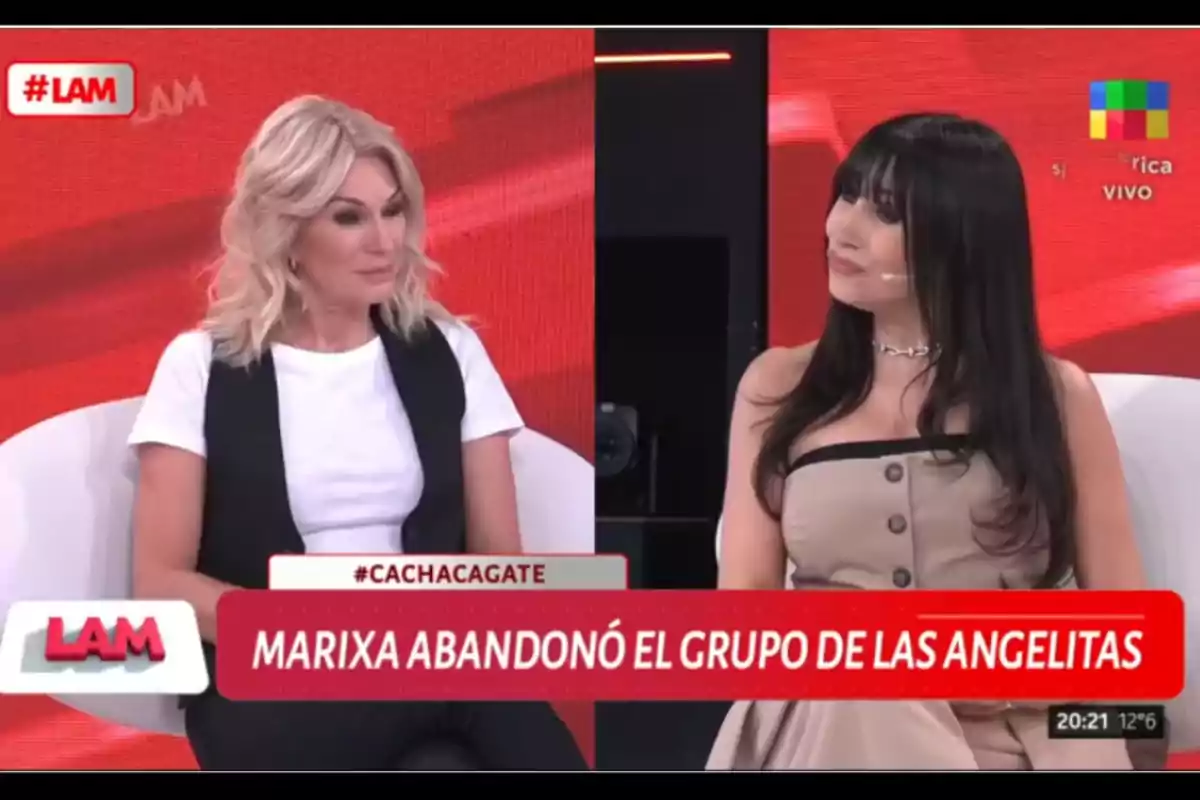 Two women sitting and talking on a television show with a red background and a sign that says Two women sitting and talking on a television show with a red background and a sign that says