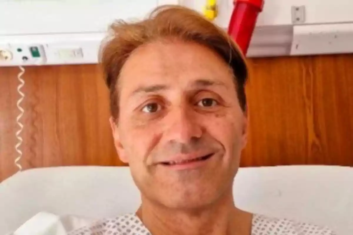 Middle-aged man in a hospital gown smiling while lying in a hospital bed Middle-aged man in a hospital gown smiling while lying in a hospital bed