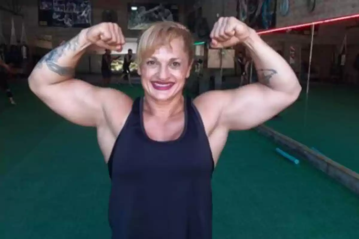 Muscular woman smiling and posing with flexed arms in a gym Muscular woman smiling and posing with flexed arms in a gym