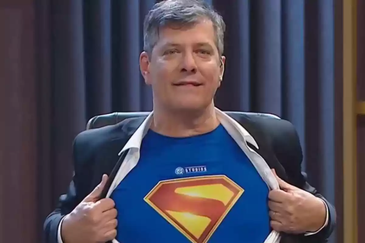 Smiling man opens his jacket and jersey to reveal a blue T-jersey with the Superman logo. Smiling man opens his jacket and jersey to reveal a blue T-jersey with the Superman logo.