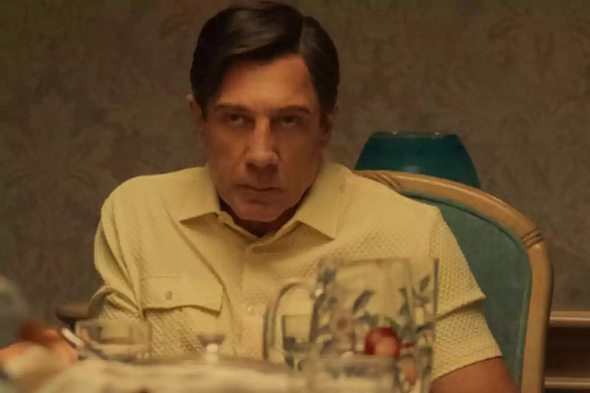 Dark-haired man with a serious expression sitting at the table with a decorated glass fielder in front of him Dark-haired man with a serious expression sitting at the table with a decorated glass fielder in front of him