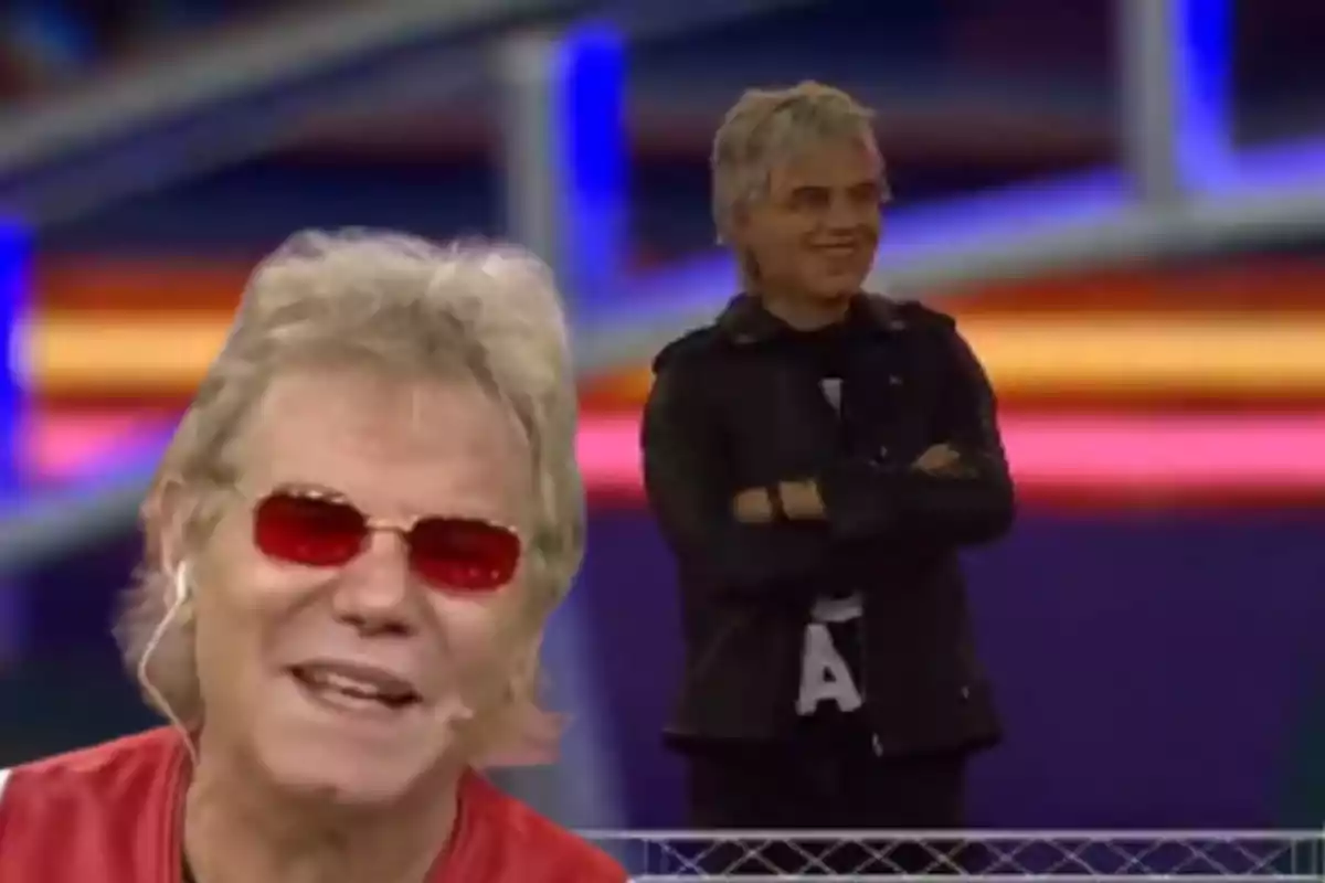 A man with red glasses smiles in the foreground while a miniature figure of himself with crossed arms appears in the background.
