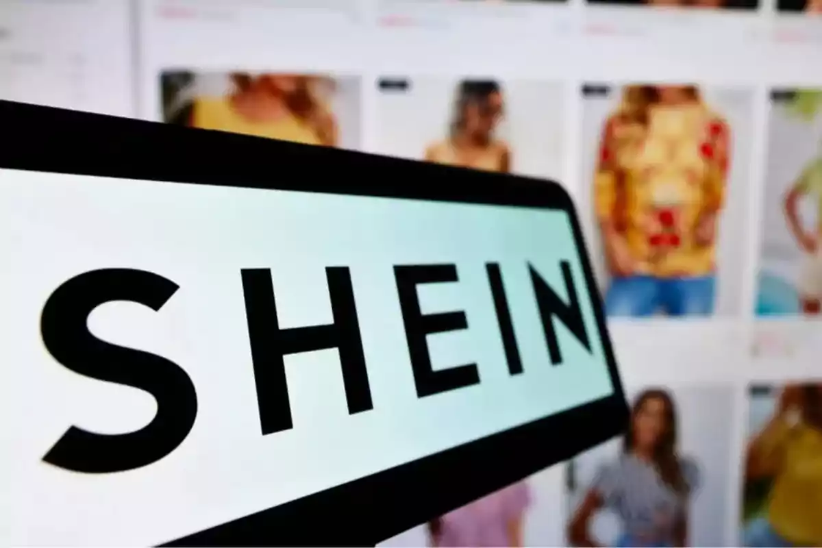 Pantalla con el logo de SHEIN en primer plano y al fondo una página web de ropa. Pantalla con el logo de SHEIN en primer plano y al fondo una página web de ropa.
