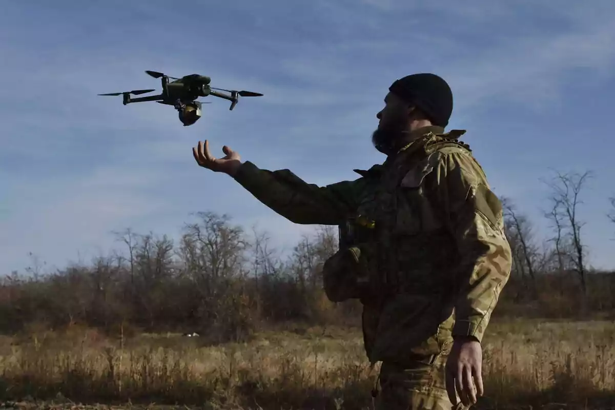 A soldier in military uniform operates a drone in an open field during the day. A soldier in military uniform operates a drone in an open field during the day.