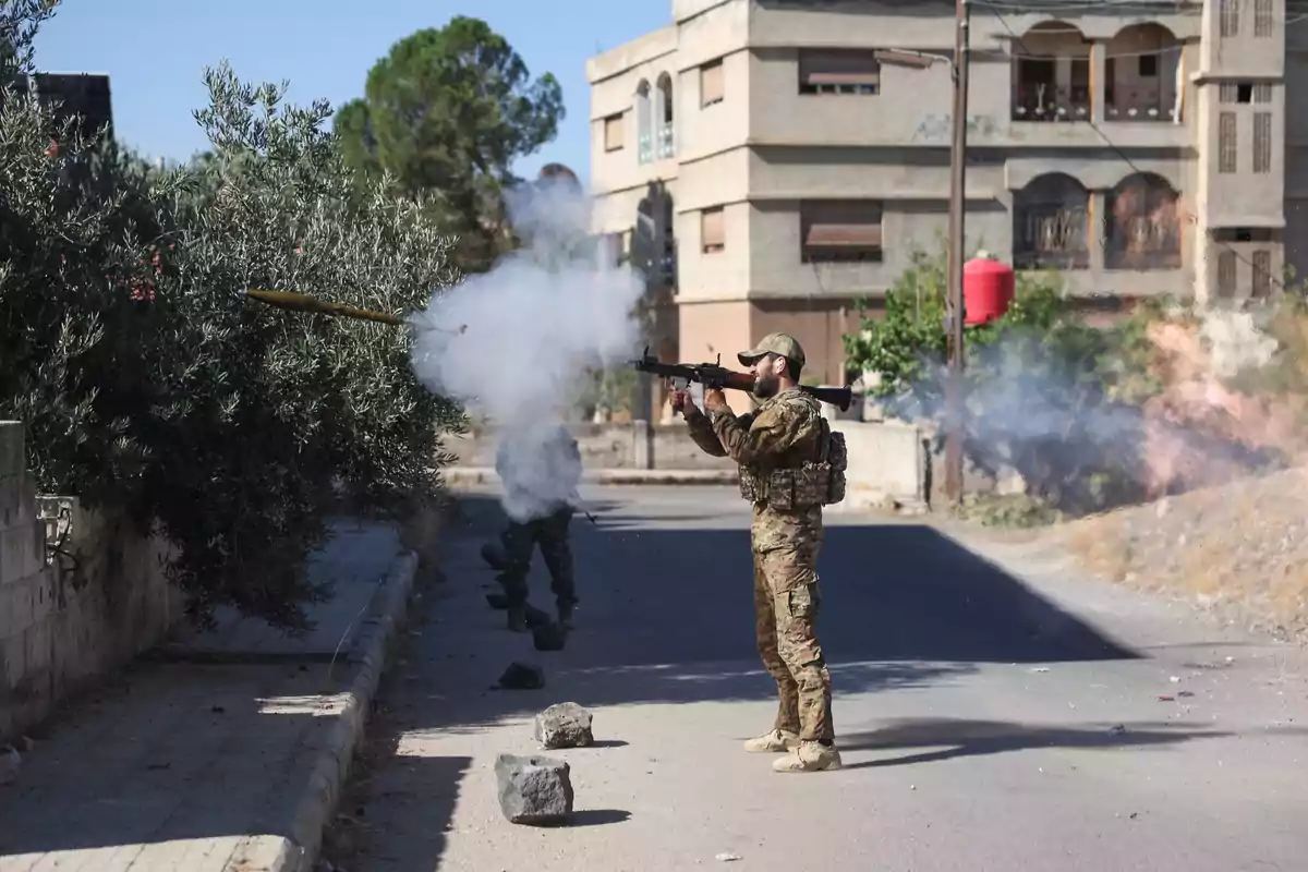 A soldier fires a rocket launcher on an urban street while another serviceman takes cover behind him, with smoke and debris on the ground. A soldier fires a rocket launcher on an urban street while another serviceman takes cover behind him, with smoke and debris on the ground.