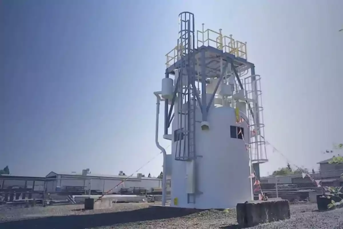 Estructura industrial blanca con escaleras y barandales amarillos ubicada en un terreno al aire libre bajo un cielo despejado Estructura industrial blanca con escaleras y barandales amarillos ubicada en un terreno al aire libre bajo un cielo despejado