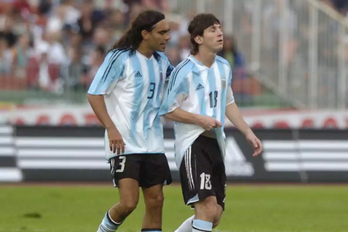 Dos futbolistas de la selección argentina con uniforme celeste y blanco en el campo de juego durante un partido