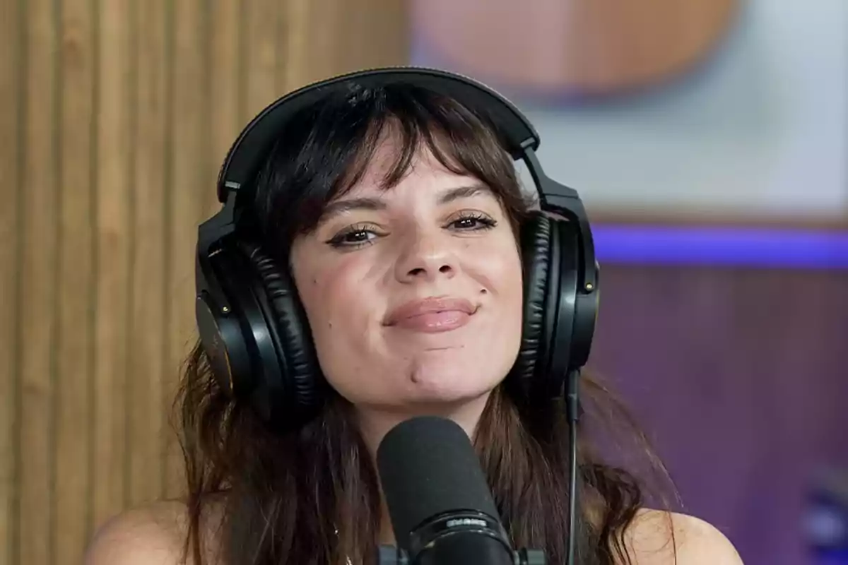 Mujer con auriculares grandes frente a un micrófono en un estudio de grabación
