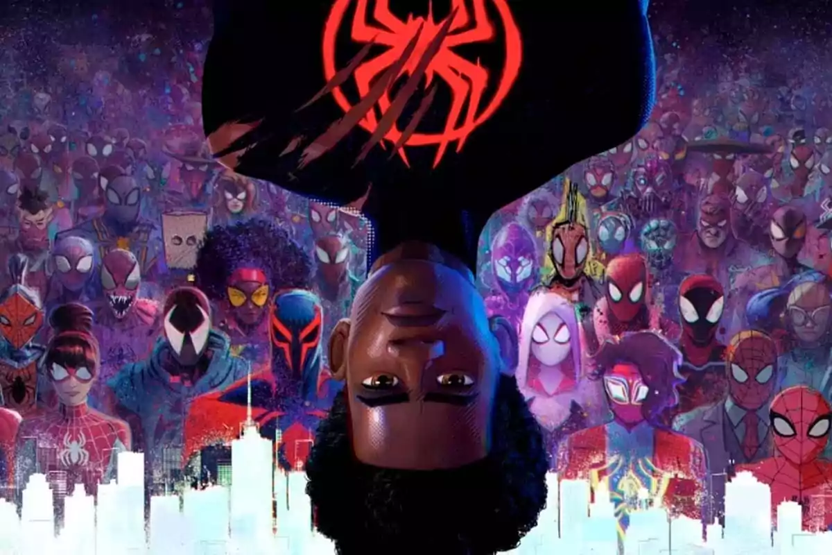 Un joven con el traje de Spider-Man aparece boca abajo en el centro de la imagen rodeado por múltiples versiones de Spider-Man de diferentes universos sobre un fondo colorido y una silueta de ciudad blanca en la parte inferior Un joven con el traje de Spider-Man aparece boca abajo en el centro de la imagen rodeado por múltiples versiones de Spider-Man de diferentes universos sobre un fondo colorido y una silueta de ciudad blanca en la parte inferior
