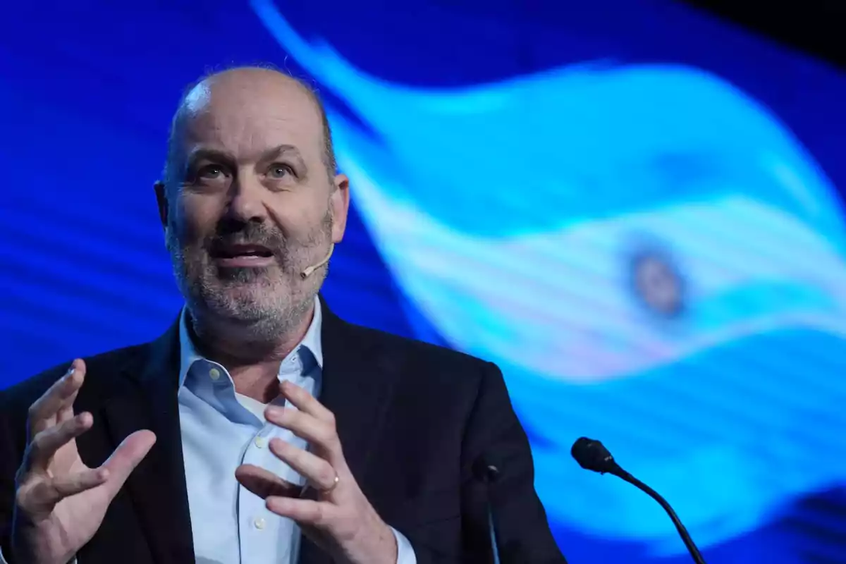 Bald man with a beard speaking in public with a headset microphone and the Argentine flag blurred in the background Bald man with a beard speaking in public with a headset microphone and the Argentine flag blurred in the background