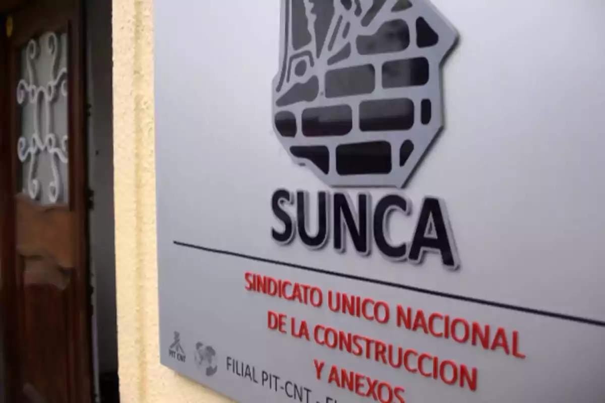 Cartel del sindicato SUNCA en una pared junto a una puerta de madera