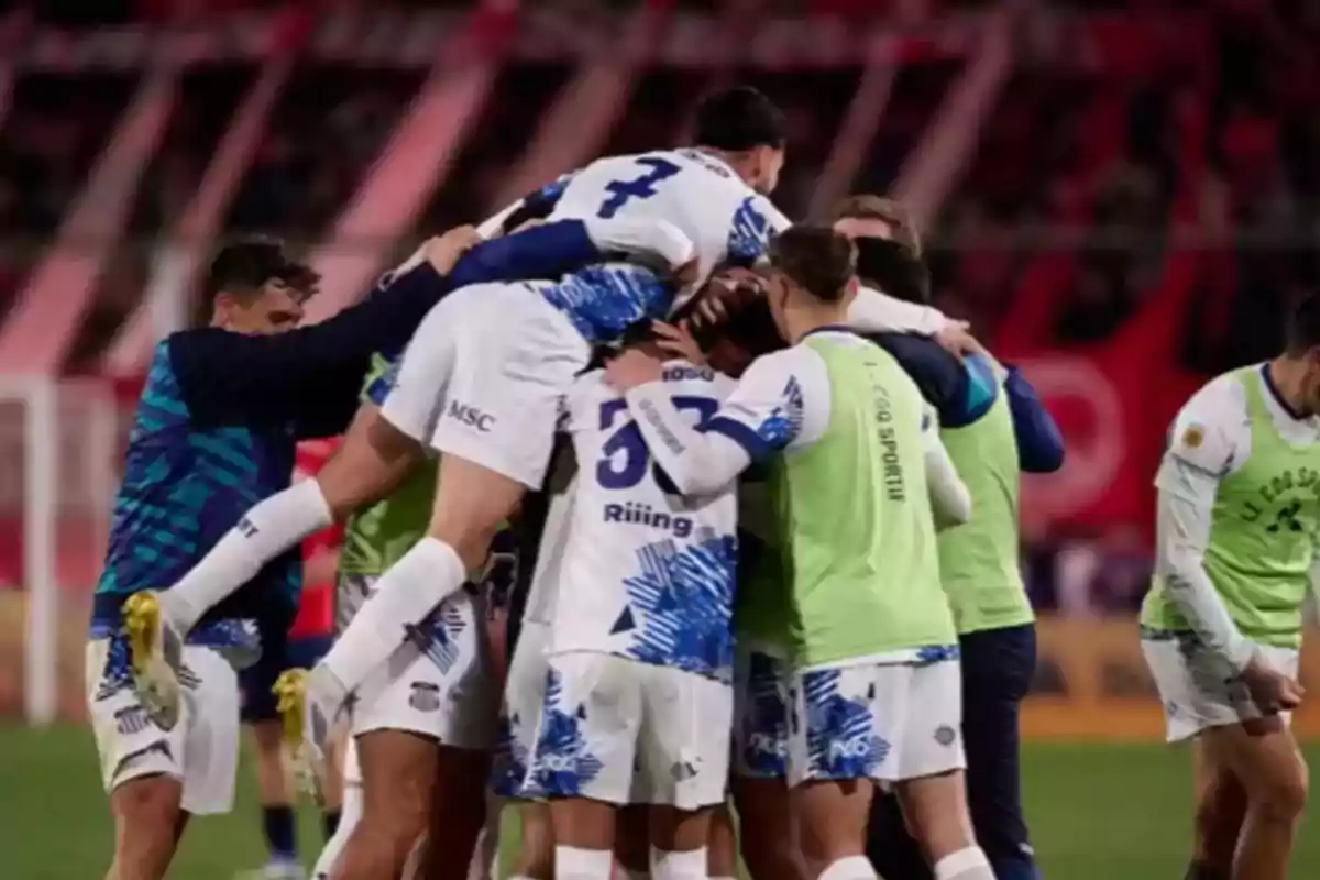 Jugadores de fútbol celebran un gol abrazándose en grupo en el campo Jugadores de fútbol celebran un gol abrazándose en grupo en el campo