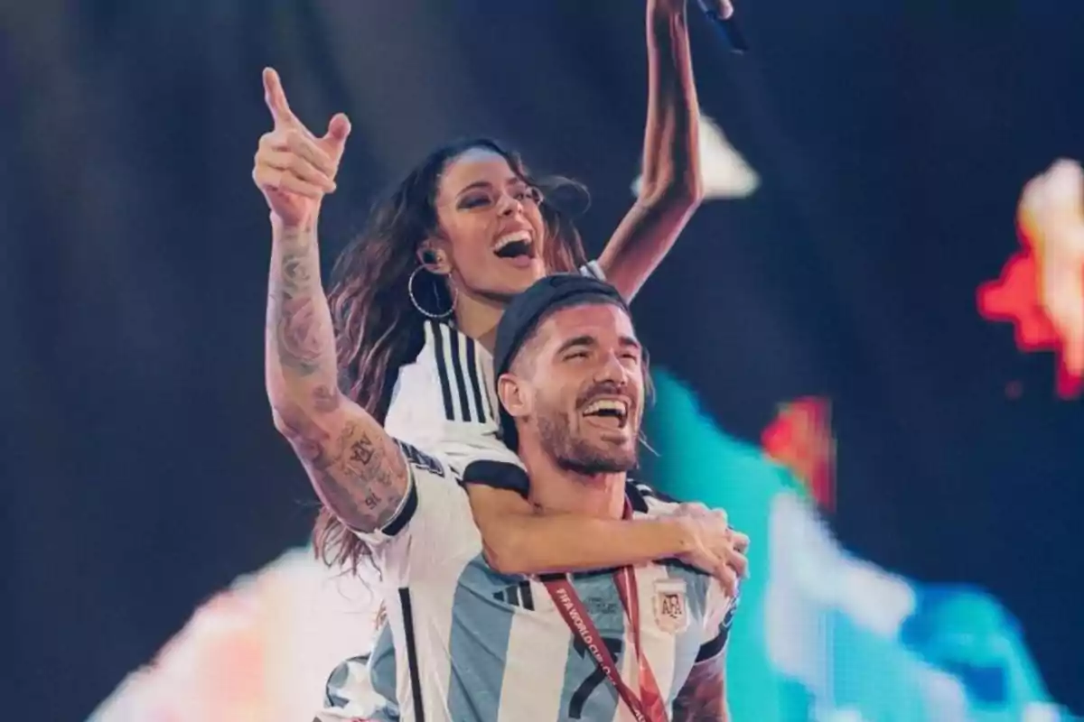Two people smile and celebrate on a stage wearing Argentina national soccer team jerseys. Two people smile and celebrate on a stage wearing Argentina national soccer team jerseys.