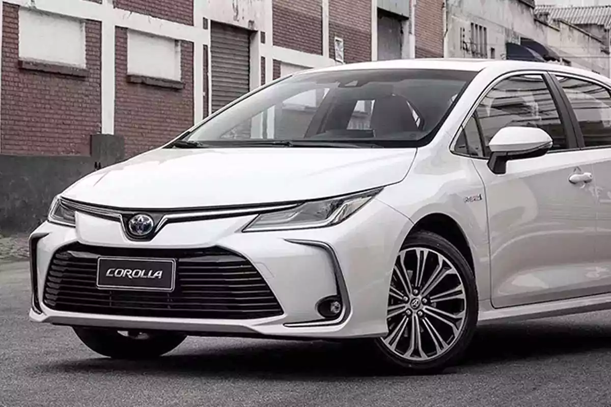 White Toyota Corolla parked on an urban street with buildings in the background White Toyota Corolla parked on an urban street with buildings in the background