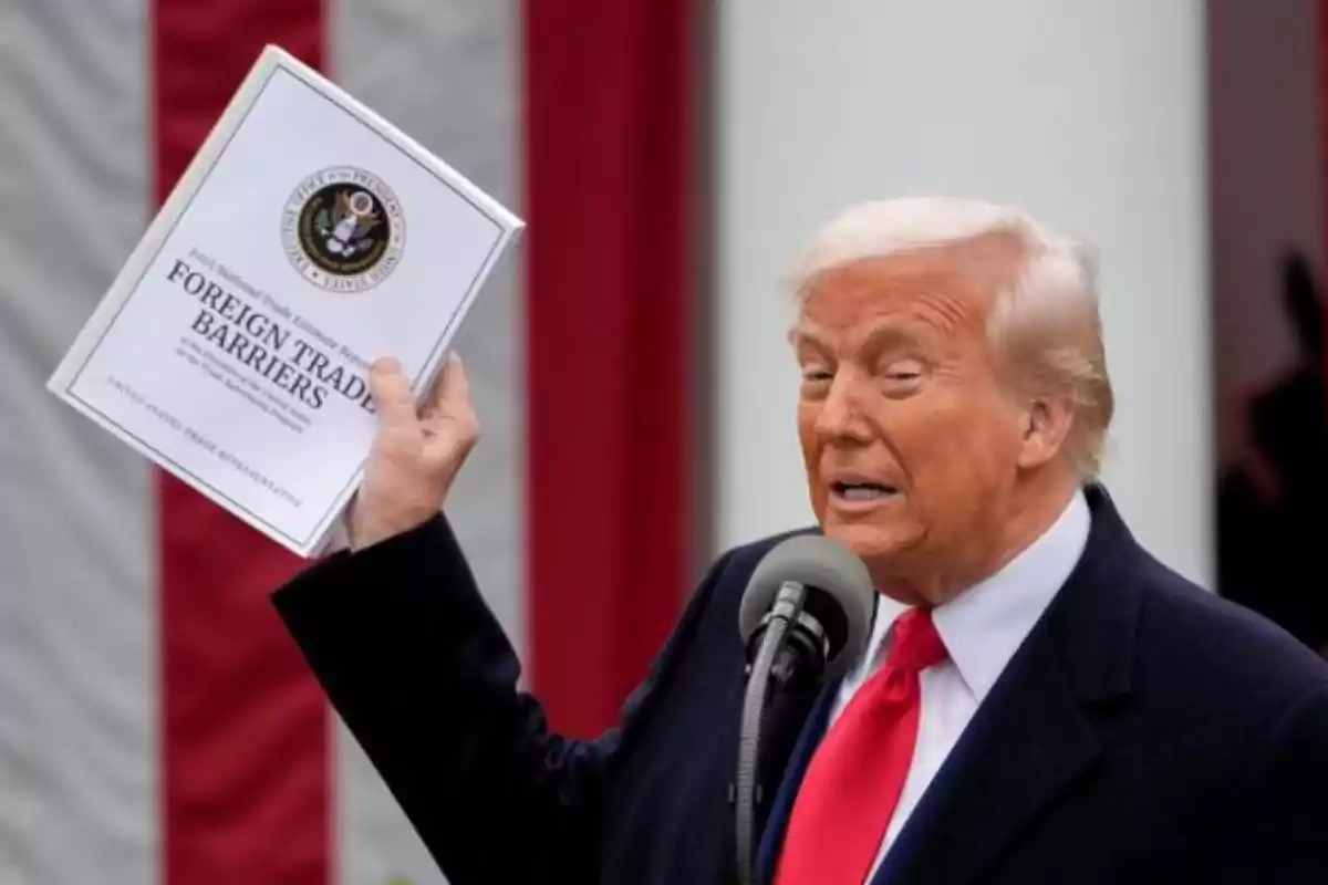 Hombre de cabello rubio con corbata roja sostiene un documento titulado Foreign Trade Barriers mientras habla frente a un micrófono Hombre de cabello rubio con corbata roja sostiene un documento titulado Foreign Trade Barriers mientras habla frente a un micrófono
