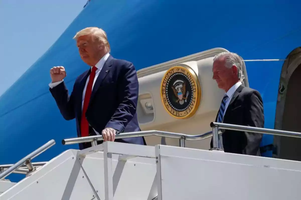 Dos hombres con traje bajan la escalinata de un avión presidencial con el sello de Estados Unidos visible al fondo Dos hombres con traje bajan la escalinata de un avión presidencial con el sello de Estados Unidos visible al fondo