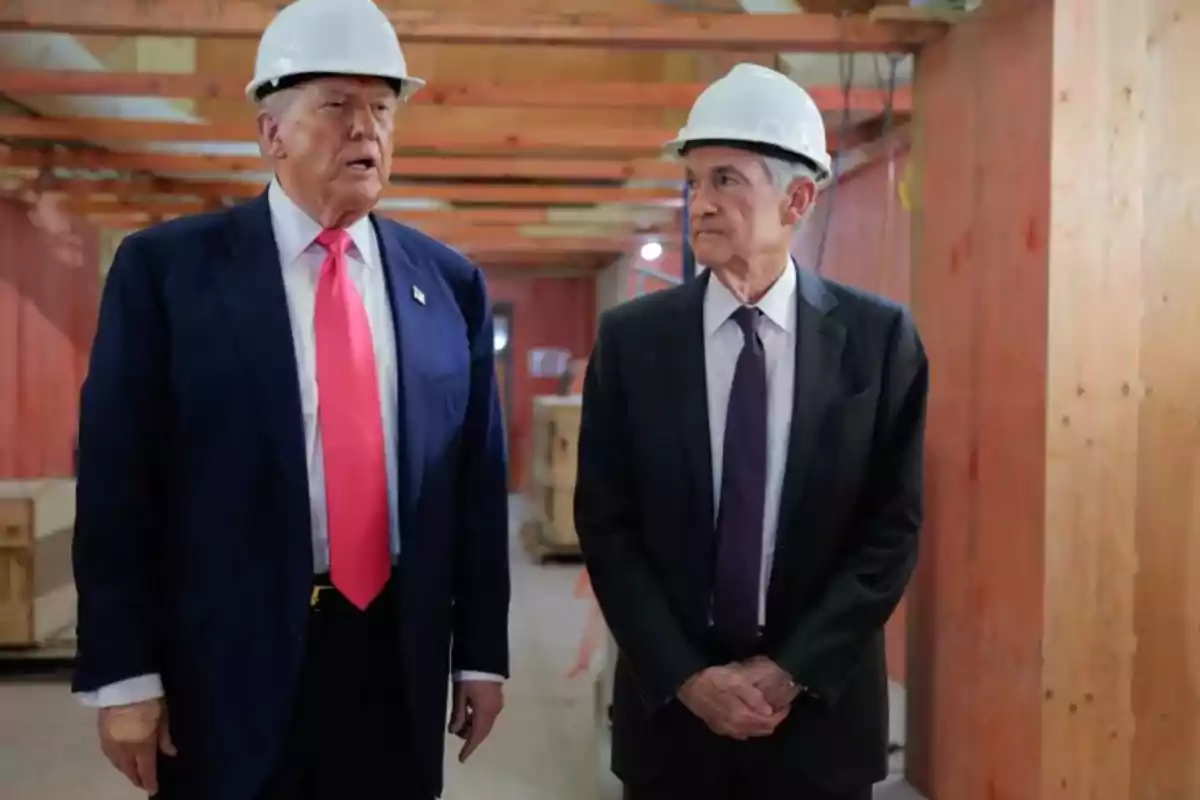 Dos hombres con casco de seguridad y traje conversan en el interior de una construcción Dos hombres con casco de seguridad y traje conversan en el interior de una construcción