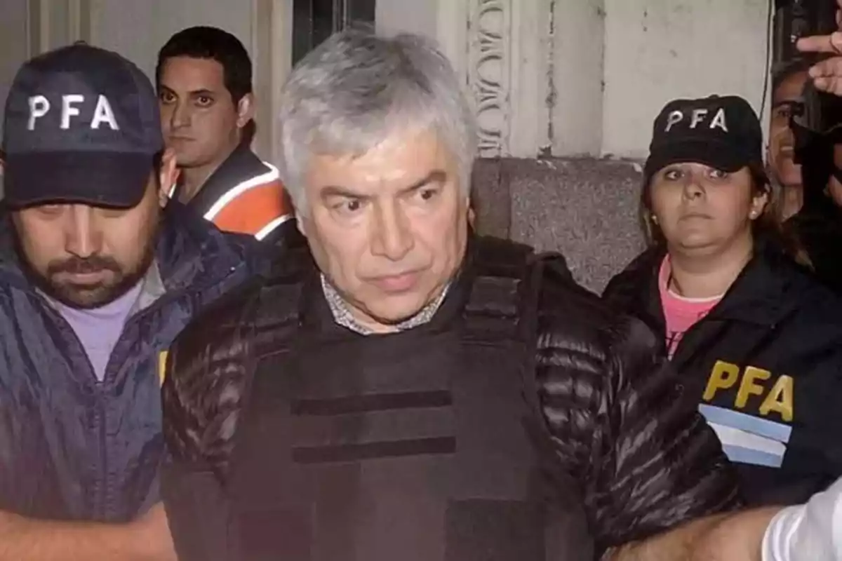 Gray-haired man escorted by Argentine federal police officers during an operation Gray-haired man escorted by Argentine federal police officers during an operation