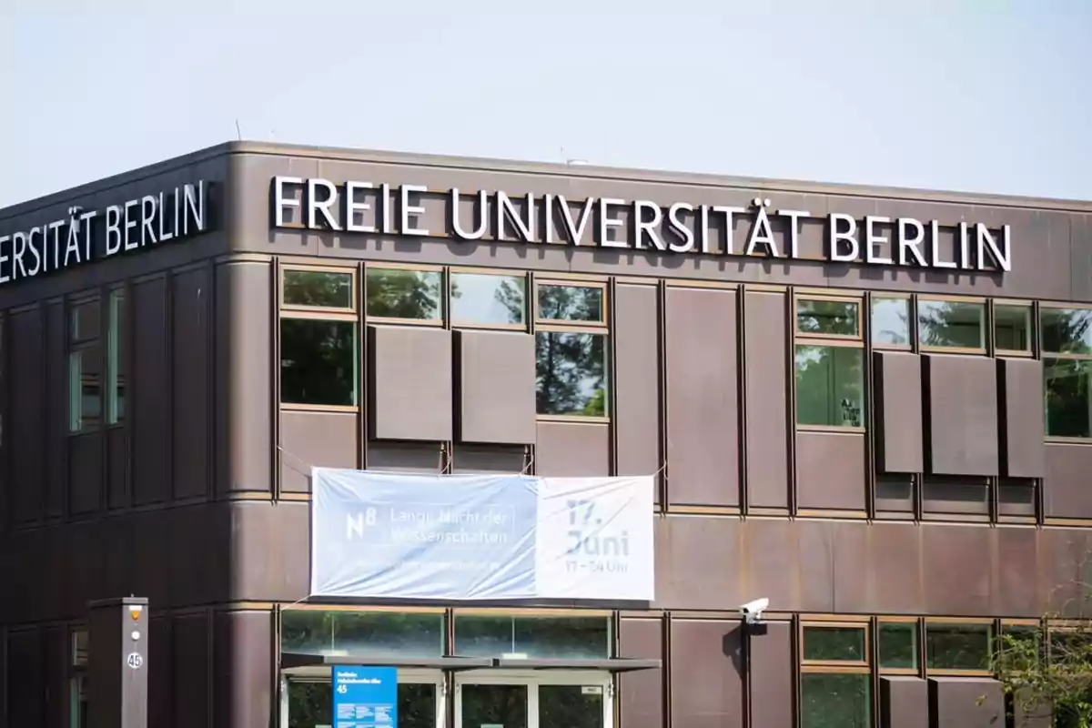 Edificio moderno de la Freie Universität Berlin con ventanas y un cartel anunciando un evento científico