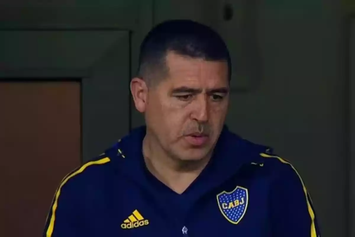 Man in a blue Boca Juniors jacket looking down with a serious expression Man in a blue Boca Juniors jacket looking down with a serious expression