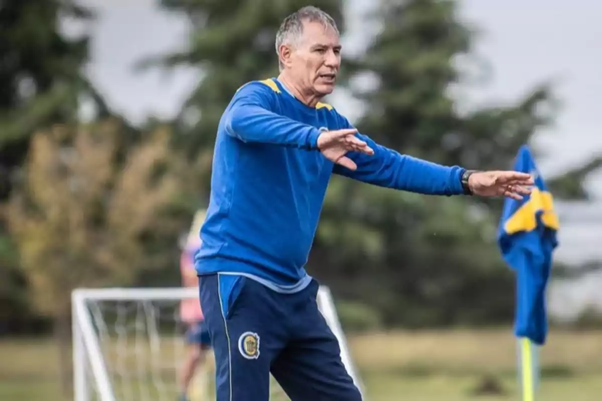 Entrenador de fútbol dando indicaciones en un campo de entrenamiento con ropa deportiva azul Entrenador de fútbol dando indicaciones en un campo de entrenamiento con ropa deportiva azul