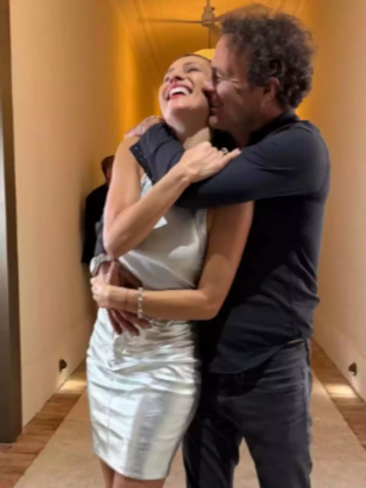 Pareja abrazándose y sonriendo en un pasillo iluminado