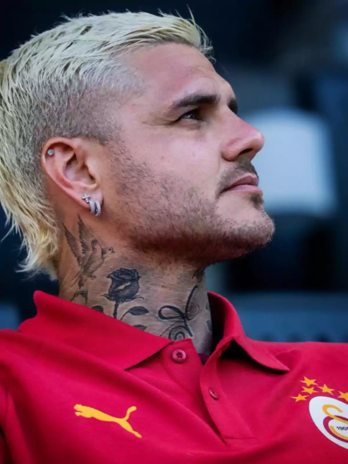 Short-haired blond man with tattoos on his neck and earrings, wearing a red t-jersey with Puma and Galatasaray logos. Short-haired blond man with tattoos on his neck and earrings, wearing a red t-jersey with Puma and Galatasaray logos.