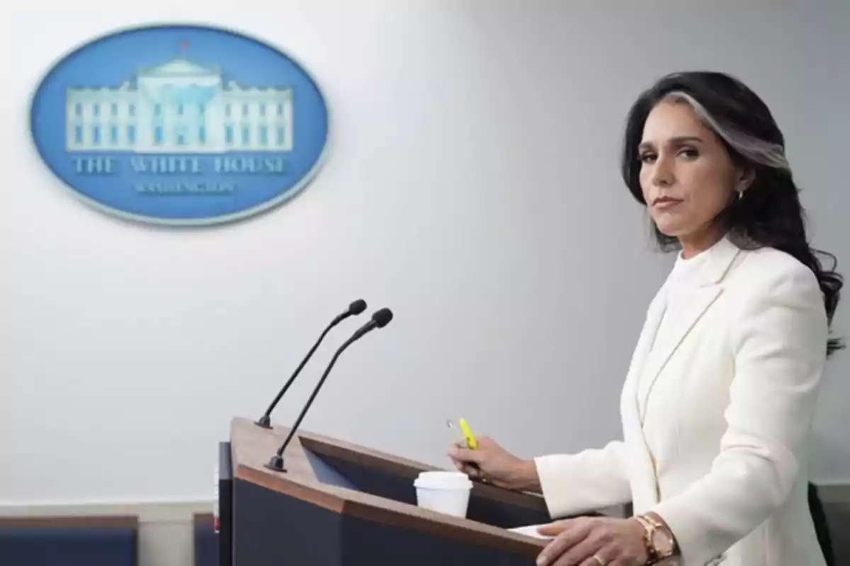 Mujer de cabello oscuro y canas vestida de blanco de pie en un podio frente a un letrero de la Casa Blanca Mujer de cabello oscuro y canas vestida de blanco de pie en un podio frente a un letrero de la Casa Blanca