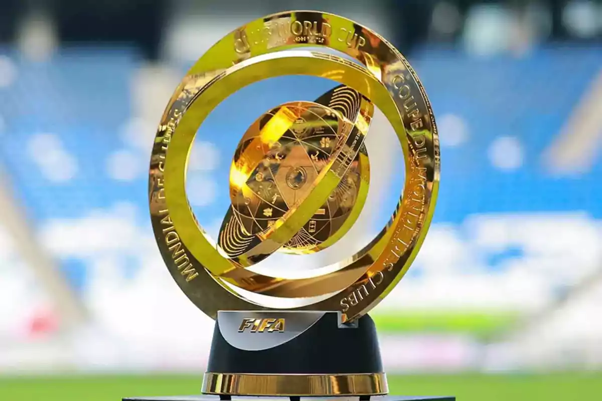 Golden FIFA Club World Cup trophy on a black base with a blurred stadium background