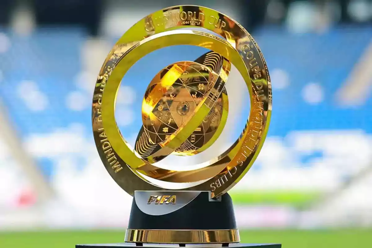 Trofeo dorado del Mundial de Clubes de la FIFA sobre una base negra con fondo de estadio desenfocado