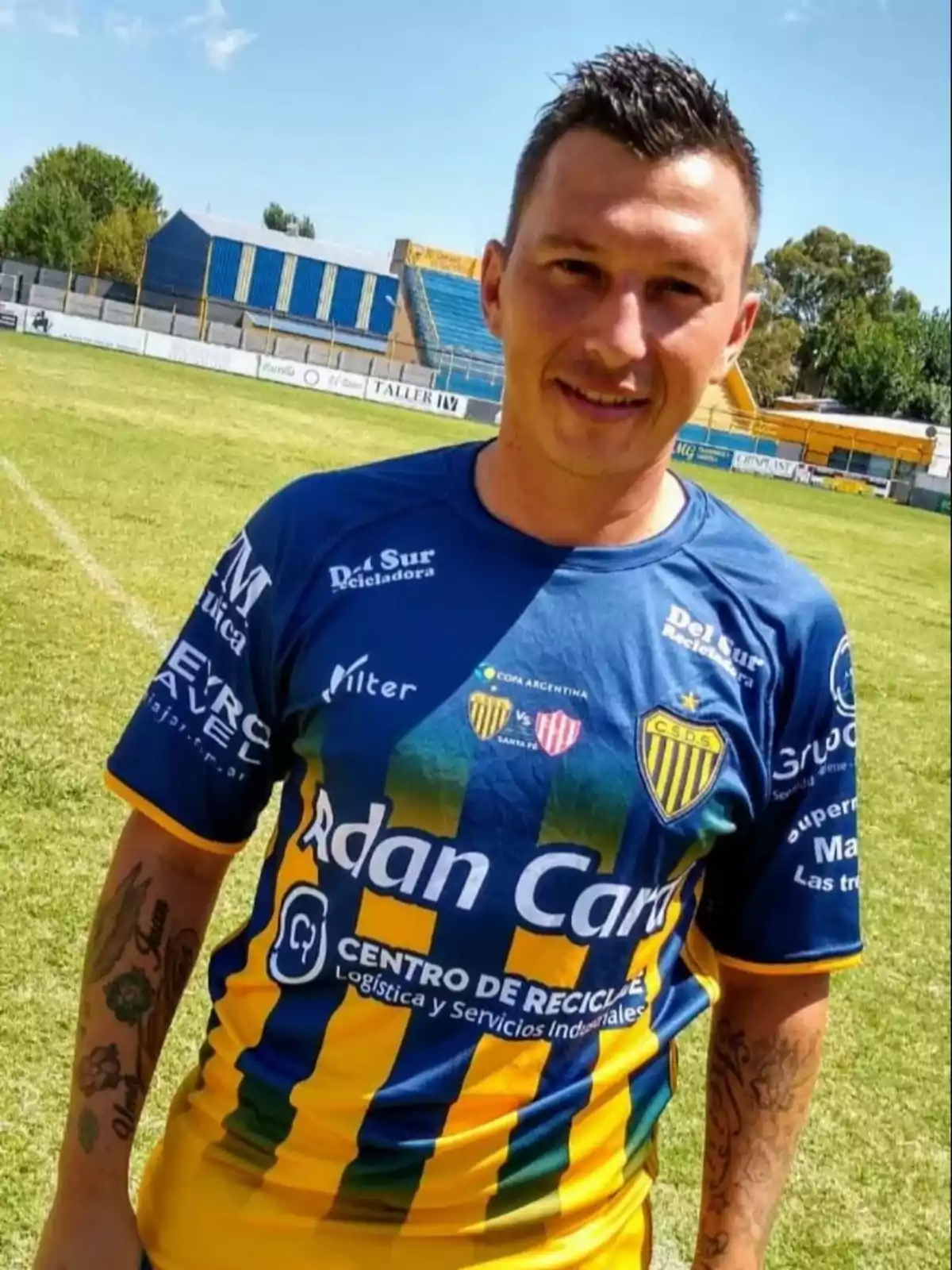 Soccer player in a blue and yellow uniform posing on a grass field during the day Soccer player in a blue and yellow uniform posing on a grass field during the day