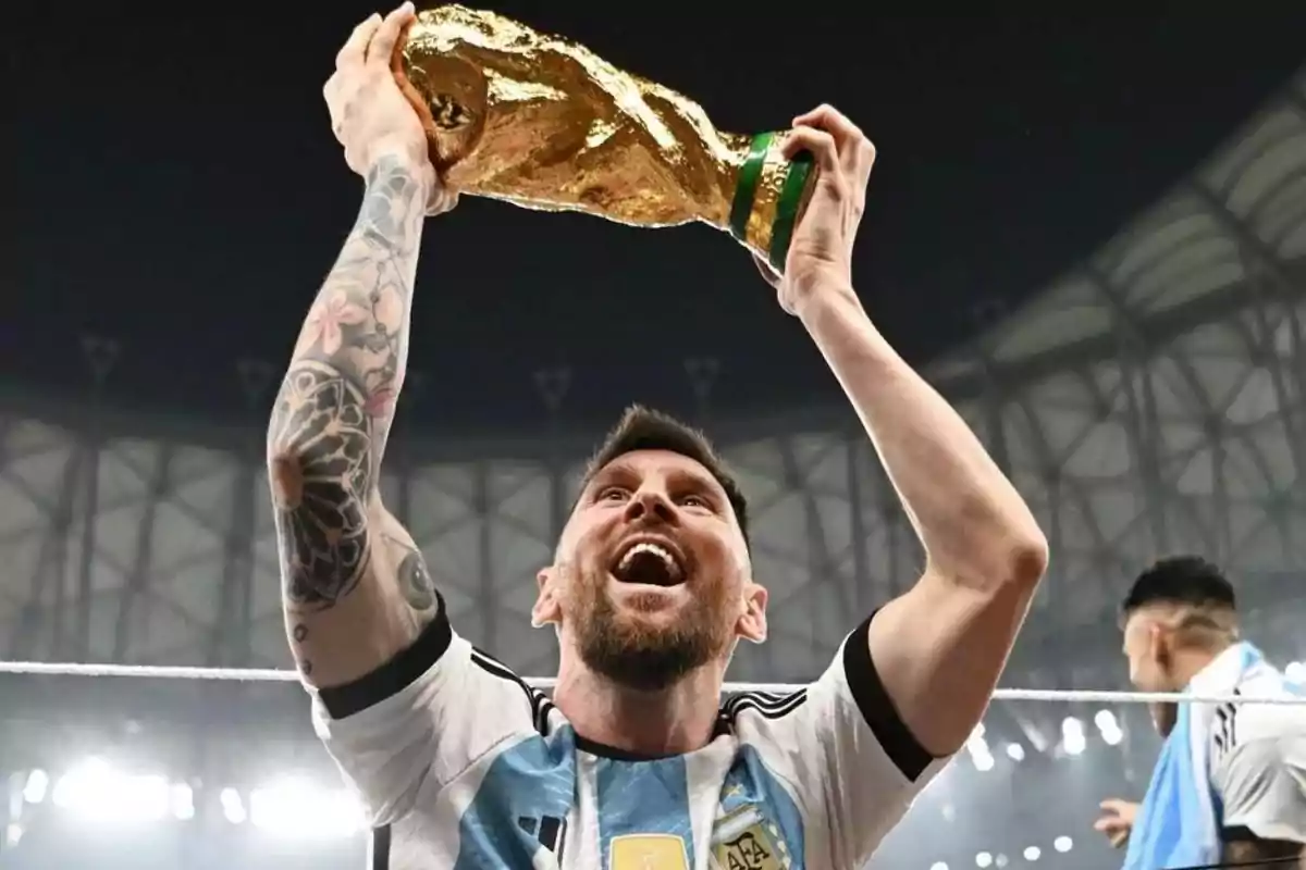 Argentinian player lifting the World Cup trophy with a joyful expression in a brightly lit stadium Argentinian player lifting the World Cup trophy with a joyful expression in a brightly lit stadium