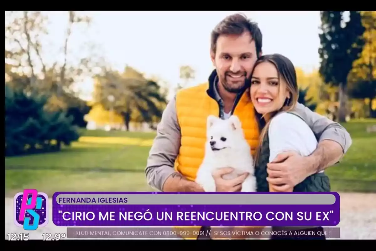 Pareja sonriente abrazada en un parque sosteniendo un perro blanco pequeño con un gráfico de programa de televisión en la parte inferior que muestra una noticia de espectáculos Pareja sonriente abrazada en un parque sosteniendo un perro blanco pequeño con un gráfico de programa de televisión en la parte inferior que muestra una noticia de espectáculos