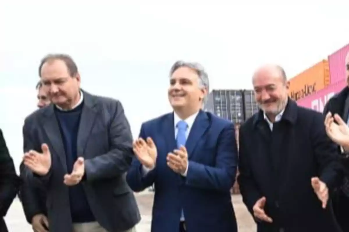 Grupo de hombres vestidos de traje aplaudiendo al aire libre con contenedores de fondo Grupo de hombres vestidos de traje aplaudiendo al aire libre con contenedores de fondo