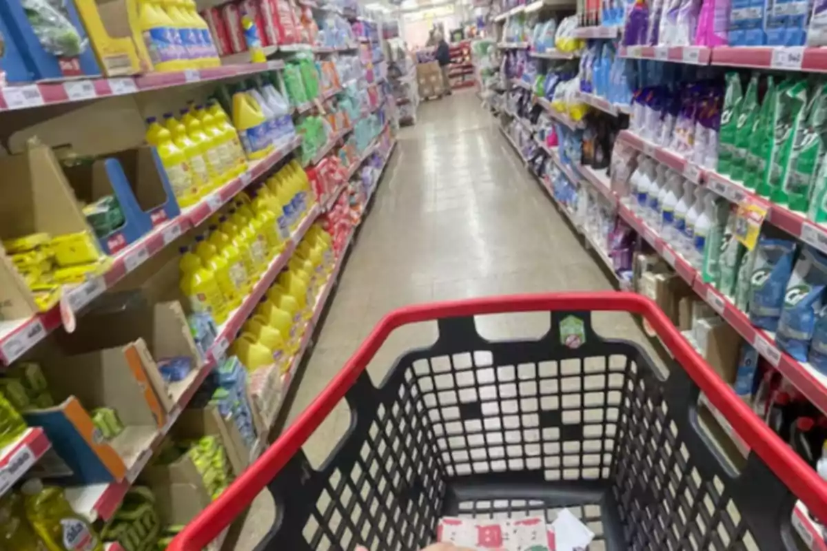 Pasillo de supermercado con productos de limpieza en los estantes y un carrito de compras en primer plano Pasillo de supermercado con productos de limpieza en los estantes y un carrito de compras en primer plano