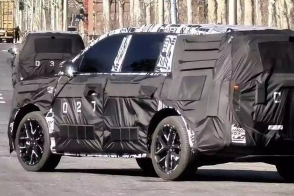 Car covered with black camouflage driving down a street during development testing Car covered with black camouflage driving down a street during development testing