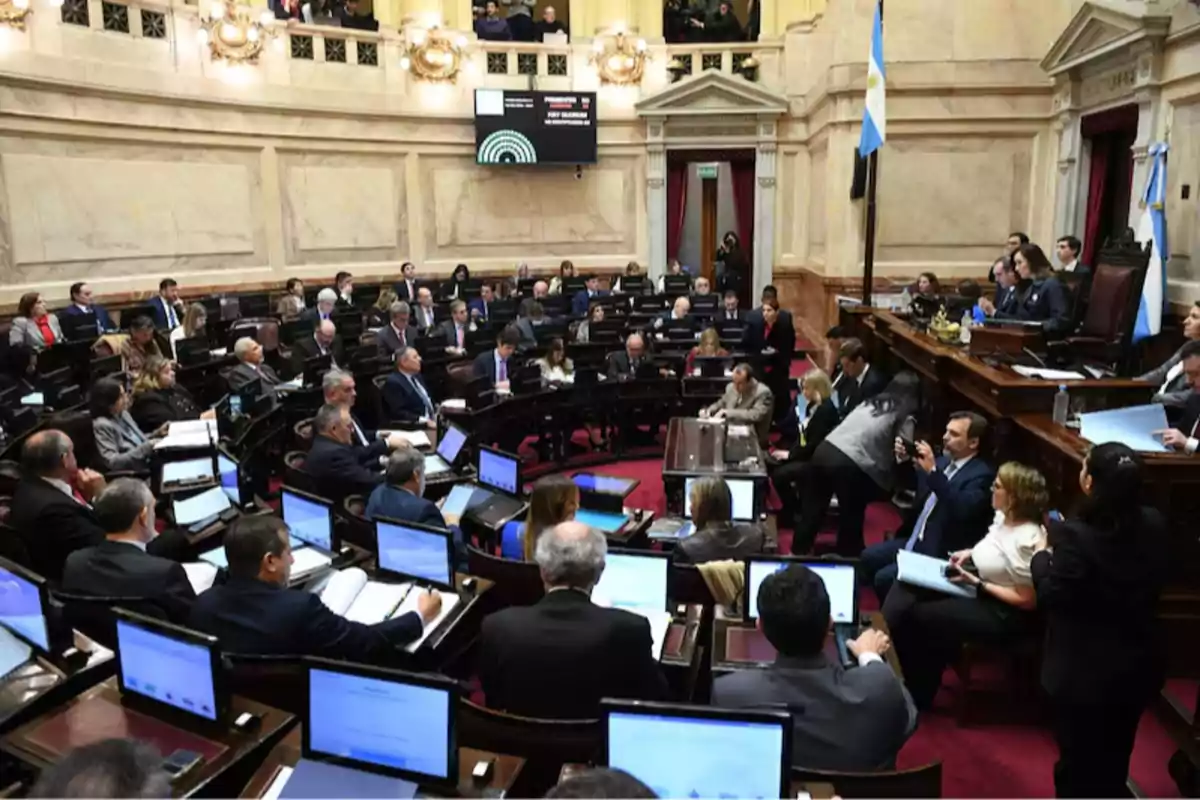 Sesión parlamentaria en el Senado de Argentina con legisladores sentados en sus bancas y computadoras encendidas mientras se desarrolla un debate Sesión parlamentaria en el Senado de Argentina con legisladores sentados en sus bancas y computadoras encendidas mientras se desarrolla un debate