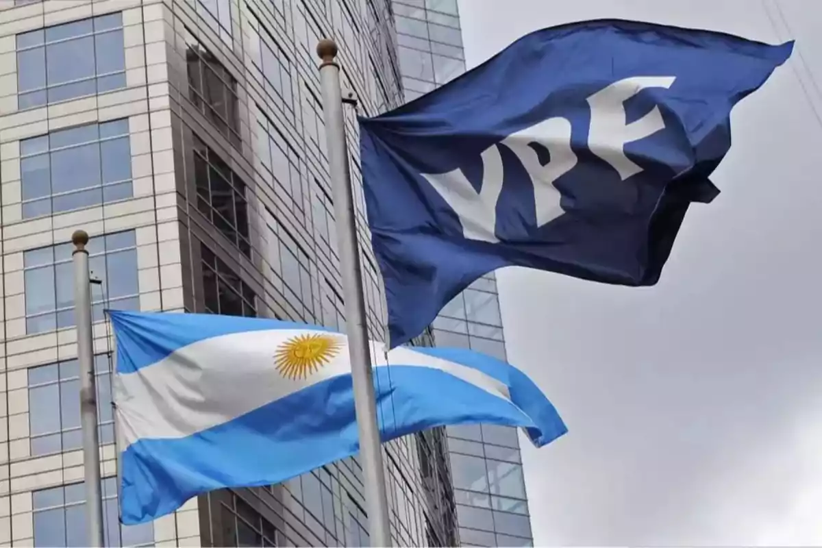 Banderas de YPF y de Argentina ondeando frente a un edificio de oficinas modernos