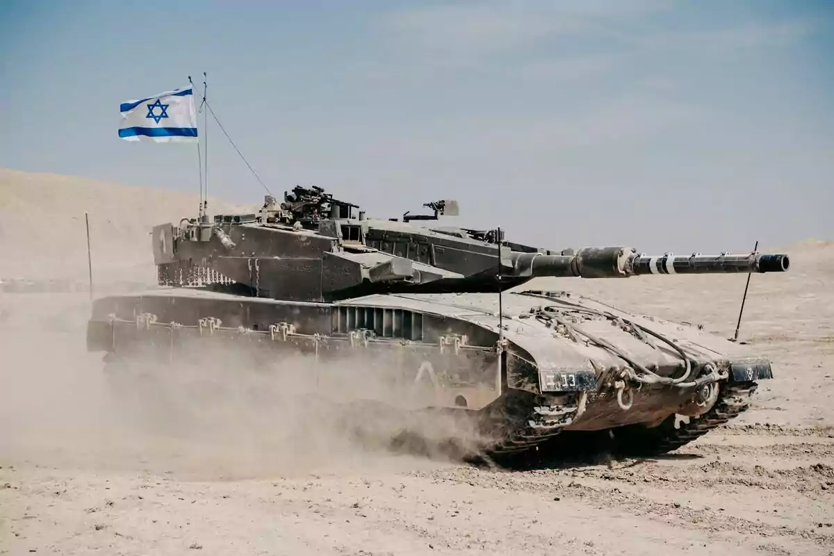 Tanque militar avanzando en terreno desértico con una bandera de Israel ondeando en la parte superior
