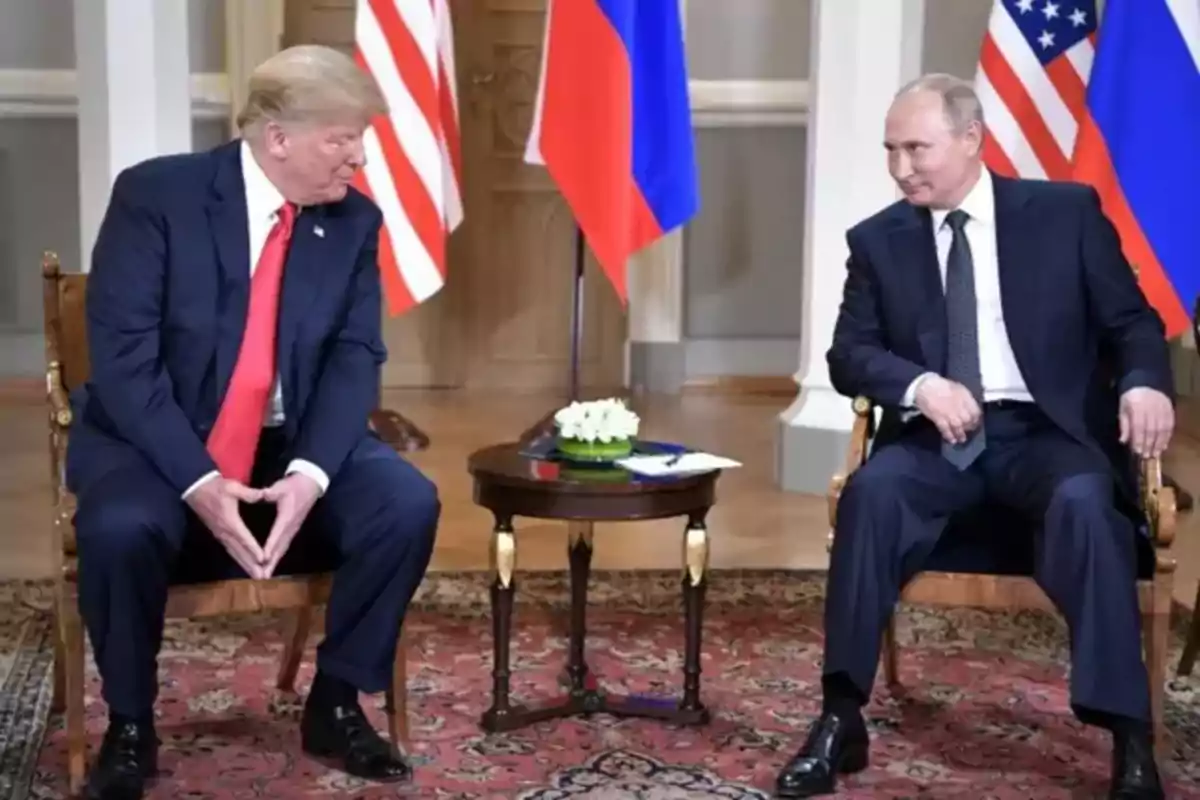 Dos hombres con traje oscuro sentados frente a frente en una sala elegante con banderas de Estados Unidos y Rusia al fondo Dos hombres con traje oscuro sentados frente a frente en una sala elegante con banderas de Estados Unidos y Rusia al fondo