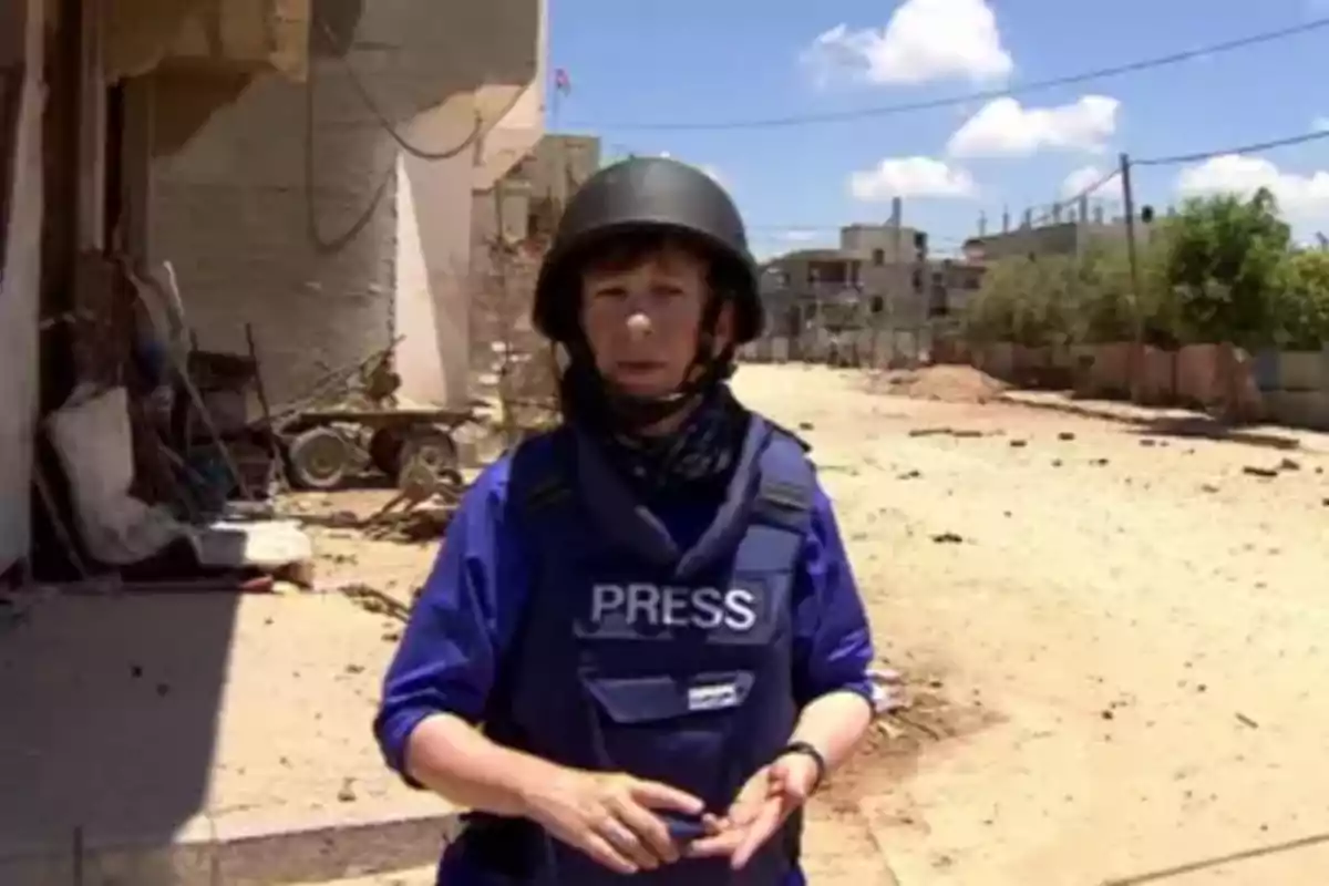 Journalist wearing a bulletproof vest and helmet in a conflict zone with buildings and rubble in the background Journalist wearing a bulletproof vest and helmet in a conflict zone with buildings and rubble in the background